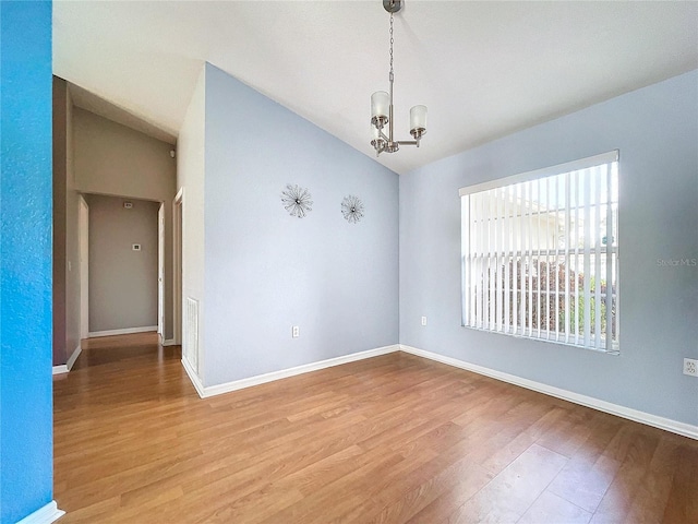 spare room with hardwood / wood-style flooring, lofted ceiling, and a chandelier