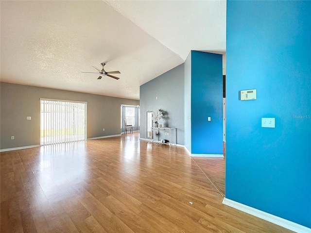 unfurnished living room with lofted ceiling, light hardwood / wood-style flooring, ceiling fan, and a textured ceiling