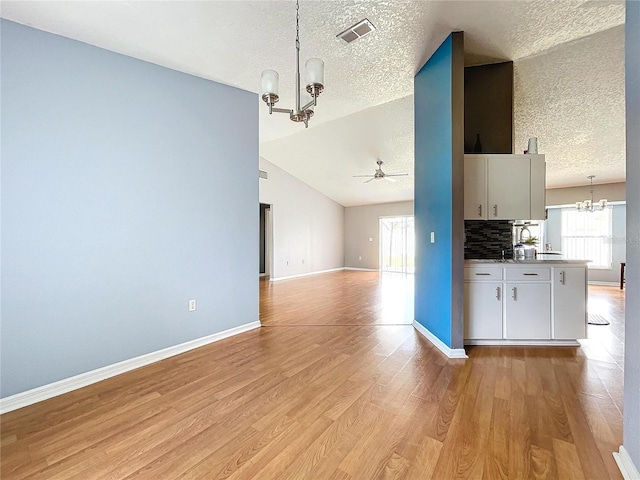 kitchen featuring a textured ceiling, decorative light fixtures, vaulted ceiling, and light hardwood / wood-style floors