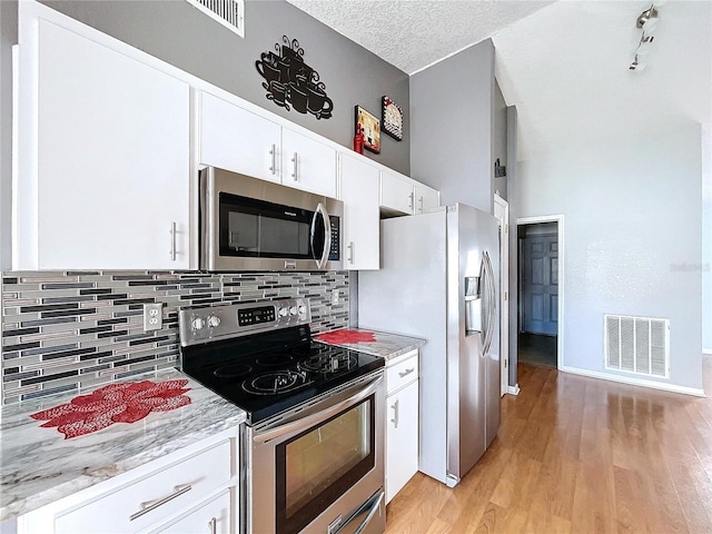 kitchen with white cabinets, light hardwood / wood-style floors, a textured ceiling, and appliances with stainless steel finishes