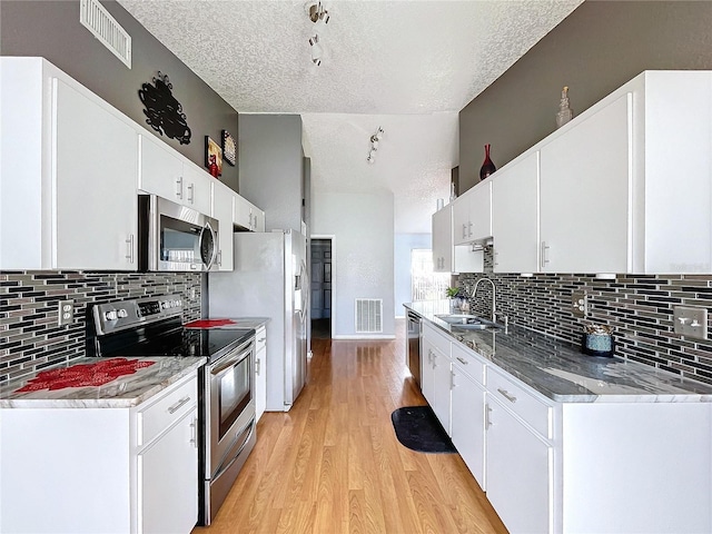 kitchen featuring sink, white cabinets, stainless steel appliances, and a textured ceiling