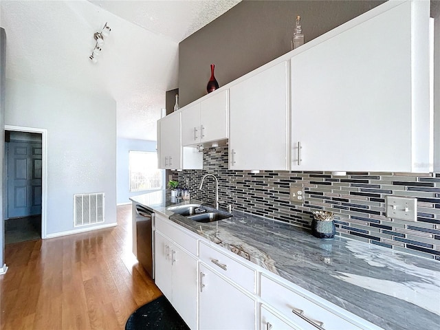 kitchen with white cabinetry, stainless steel dishwasher, light hardwood / wood-style floors, and sink