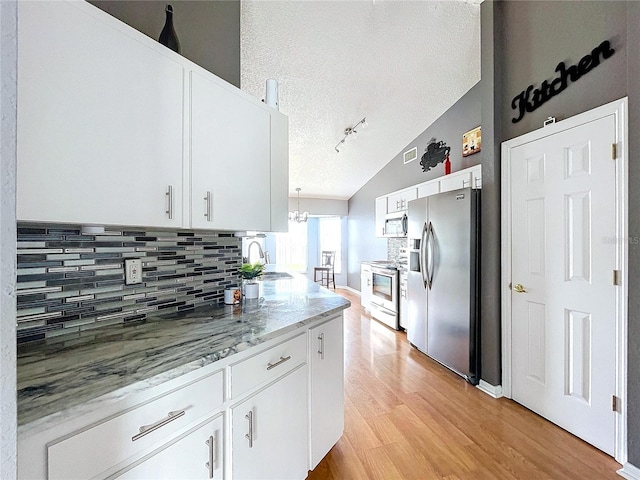 kitchen featuring vaulted ceiling, white cabinetry, stainless steel appliances, and a textured ceiling