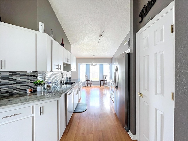 kitchen with white cabinetry, sink, hanging light fixtures, a textured ceiling, and appliances with stainless steel finishes