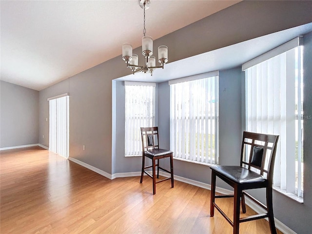 living area featuring light hardwood / wood-style flooring, a chandelier, and vaulted ceiling