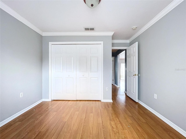 unfurnished bedroom featuring a closet, ornamental molding, and light hardwood / wood-style flooring