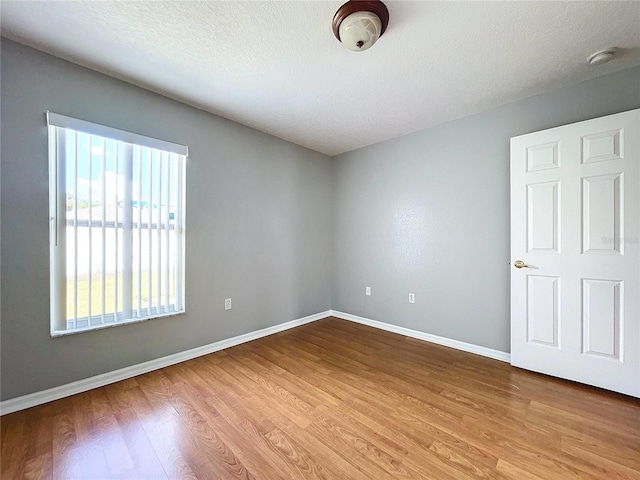 spare room with light wood-type flooring and a textured ceiling