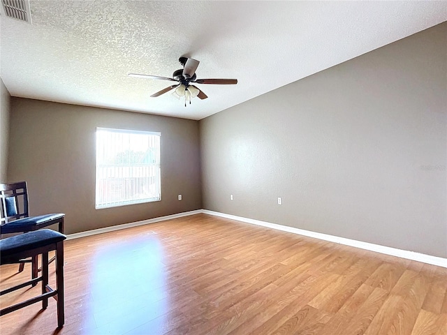 spare room with ceiling fan, light hardwood / wood-style floors, and a textured ceiling