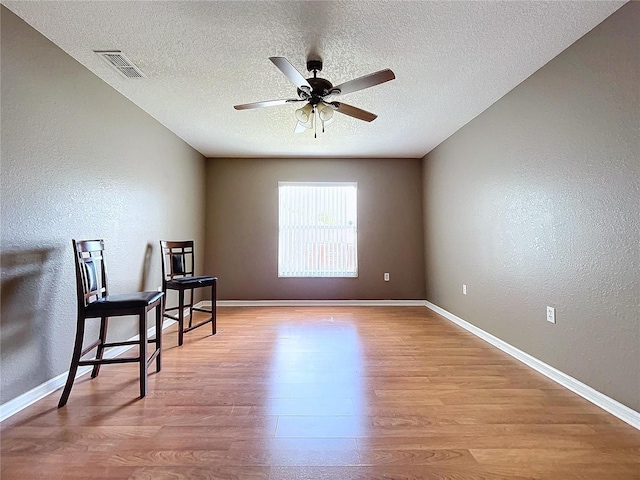 living area featuring a textured ceiling, light hardwood / wood-style flooring, and ceiling fan