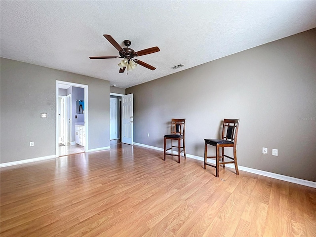 unfurnished room with a textured ceiling, light hardwood / wood-style flooring, and ceiling fan