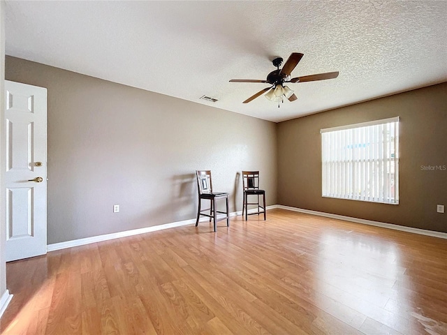 interior space with ceiling fan, a textured ceiling, and light hardwood / wood-style flooring