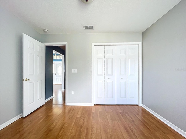 unfurnished bedroom featuring hardwood / wood-style floors, a textured ceiling, and a closet