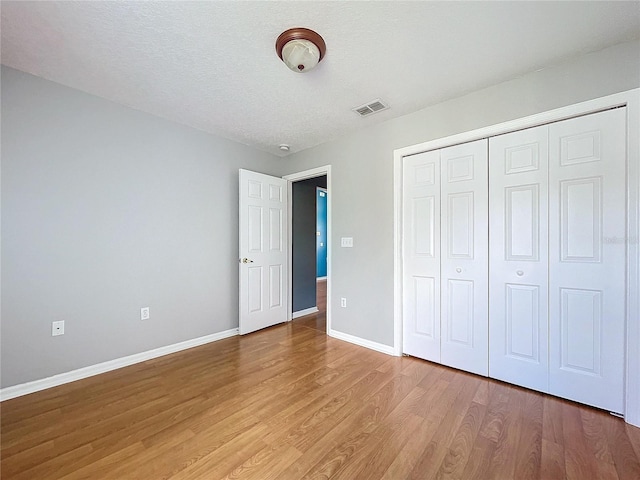 unfurnished bedroom with hardwood / wood-style flooring, a textured ceiling, and a closet