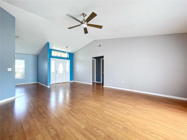 interior space with ceiling fan, lofted ceiling, a textured ceiling, and light hardwood / wood-style flooring