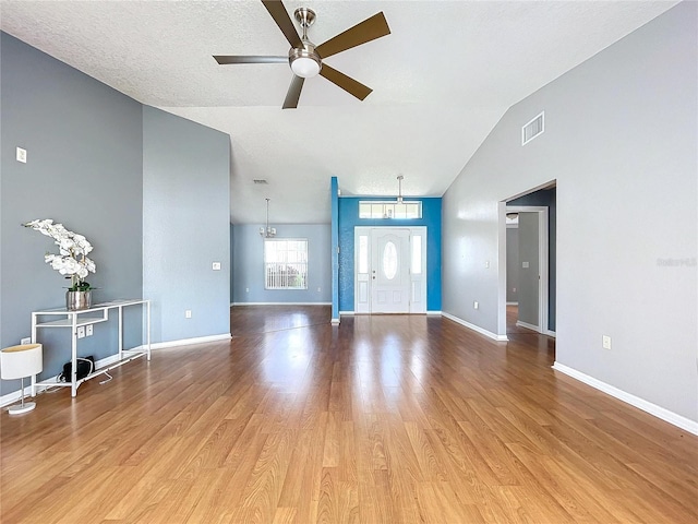 unfurnished living room with hardwood / wood-style floors, a textured ceiling, vaulted ceiling, and ceiling fan