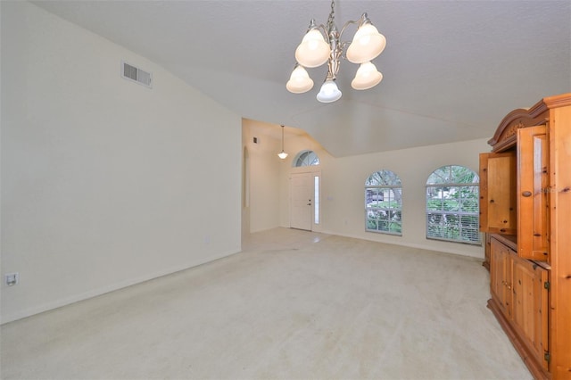 unfurnished living room featuring light colored carpet, vaulted ceiling, and a chandelier