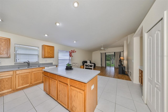 kitchen featuring vaulted ceiling, ceiling fan, a kitchen island, sink, and light tile patterned flooring