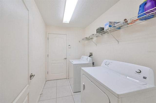 laundry area with separate washer and dryer, a textured ceiling, and light tile patterned floors