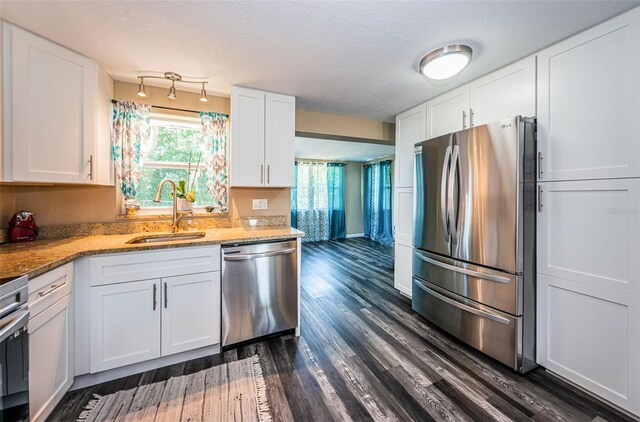 kitchen featuring white cabinetry, dark hardwood / wood-style flooring, sink, appliances with stainless steel finishes, and a textured ceiling