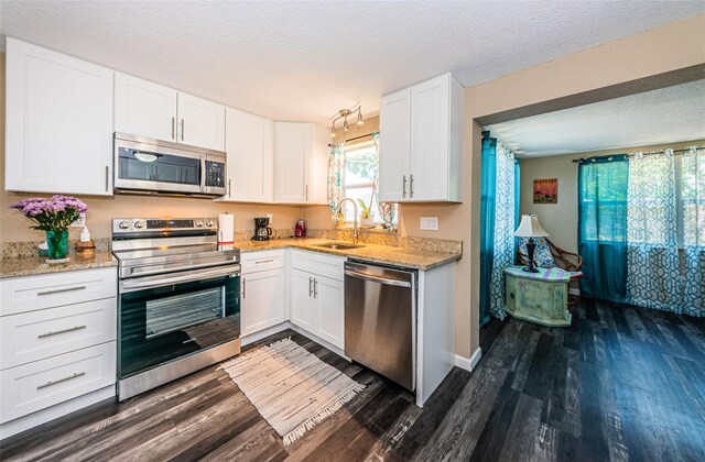 kitchen featuring sink, a textured ceiling, white cabinetry, appliances with stainless steel finishes, and dark hardwood / wood-style floors