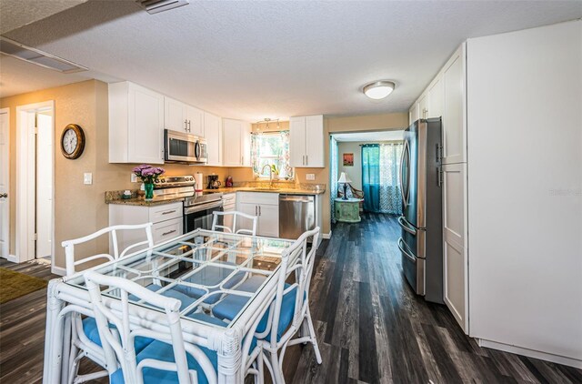 kitchen with white cabinets, sink, a textured ceiling, stainless steel appliances, and dark hardwood / wood-style floors