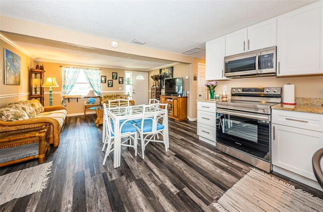 kitchen featuring stainless steel appliances, dark hardwood / wood-style floors, a textured ceiling, and white cabinetry