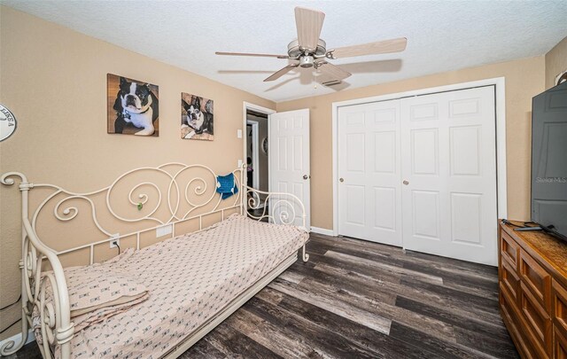 bedroom with ceiling fan, a textured ceiling, a closet, and dark wood-type flooring