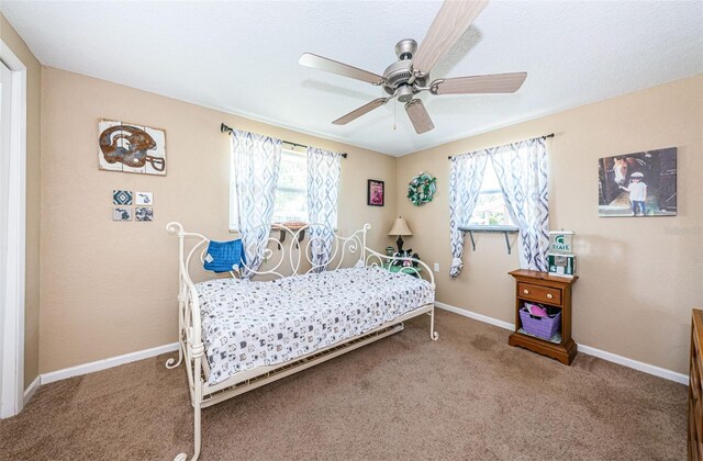 carpeted bedroom with ceiling fan and multiple windows