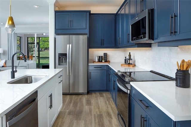 kitchen featuring wood-type flooring, blue cabinetry, sink, pendant lighting, and appliances with stainless steel finishes