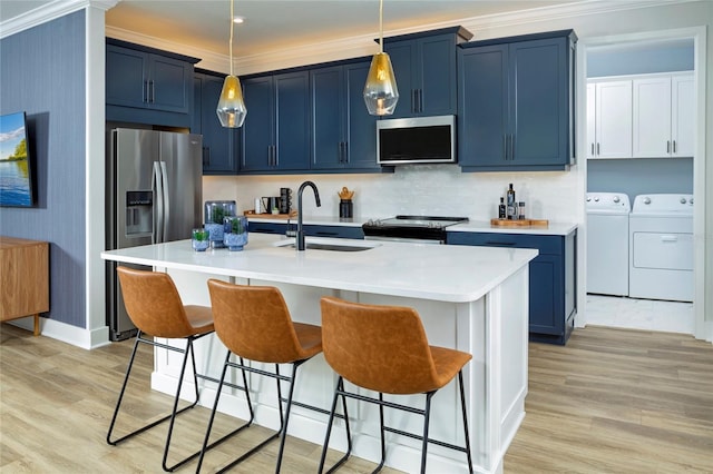 kitchen with an island with sink, sink, blue cabinetry, appliances with stainless steel finishes, and independent washer and dryer