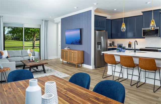 kitchen with blue cabinetry, light hardwood / wood-style flooring, a breakfast bar, sink, and stainless steel appliances