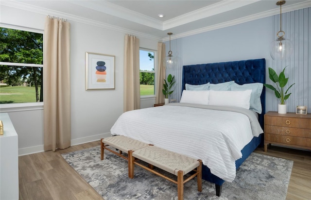 bedroom featuring crown molding, light wood-type flooring, and a tray ceiling