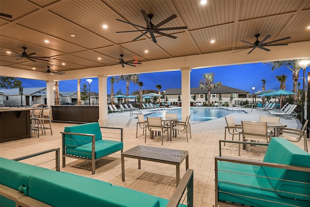 view of swimming pool with ceiling fan, exterior bar, and a patio