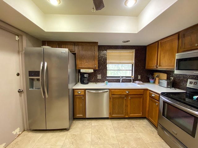 kitchen featuring appliances with stainless steel finishes, tasteful backsplash, sink, and a raised ceiling