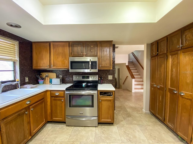 kitchen featuring sink, decorative backsplash, appliances with stainless steel finishes, and light tile patterned flooring