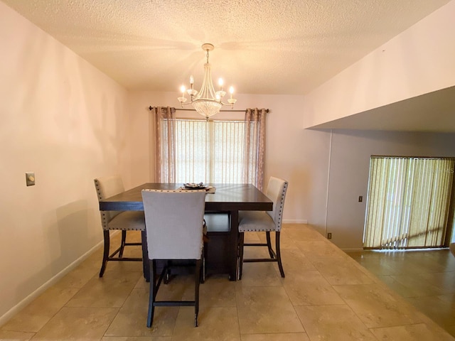 dining space featuring a chandelier, a textured ceiling, and baseboards