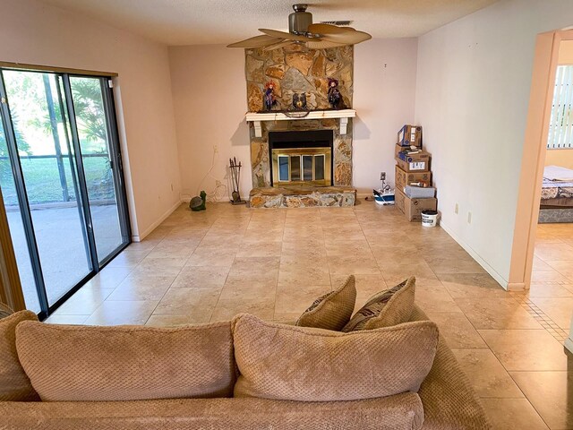 tiled living area with a ceiling fan, lofted ceiling, a fireplace, and baseboards