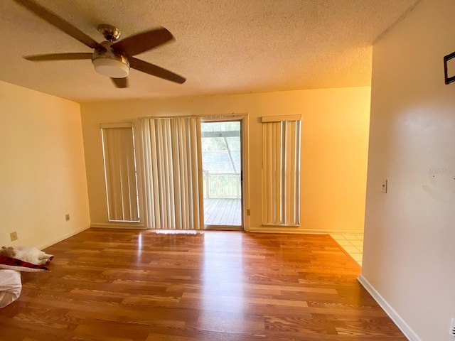 empty room with a ceiling fan, a textured ceiling, baseboards, and wood finished floors