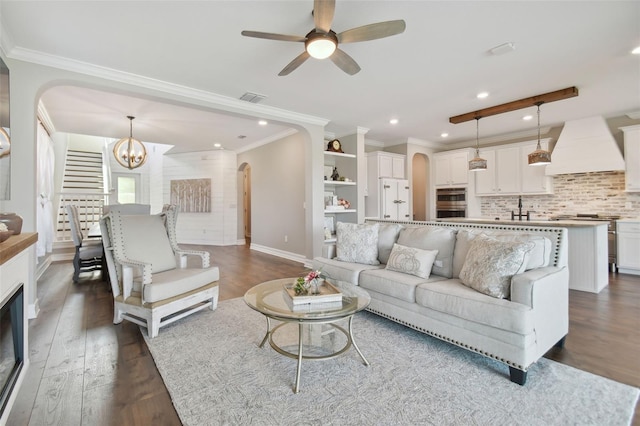 living room with sink, crown molding, dark hardwood / wood-style floors, and ceiling fan with notable chandelier