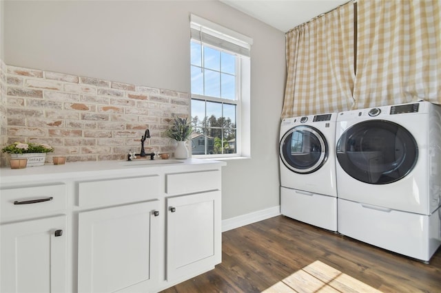 laundry room featuring cabinets, independent washer and dryer, dark hardwood / wood-style floors, sink, and brick wall