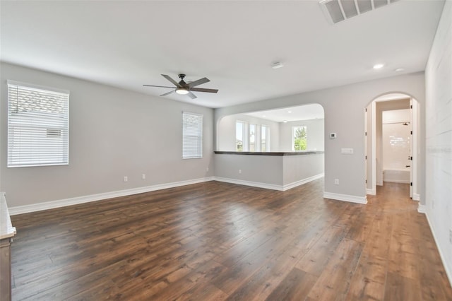 unfurnished living room featuring dark wood-type flooring and ceiling fan