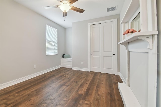 unfurnished bedroom with a closet, dark wood-type flooring, and ceiling fan