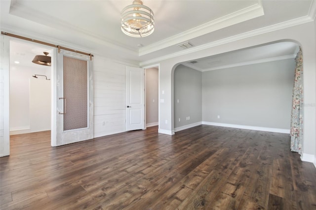 spare room with crown molding, a raised ceiling, and dark hardwood / wood-style floors