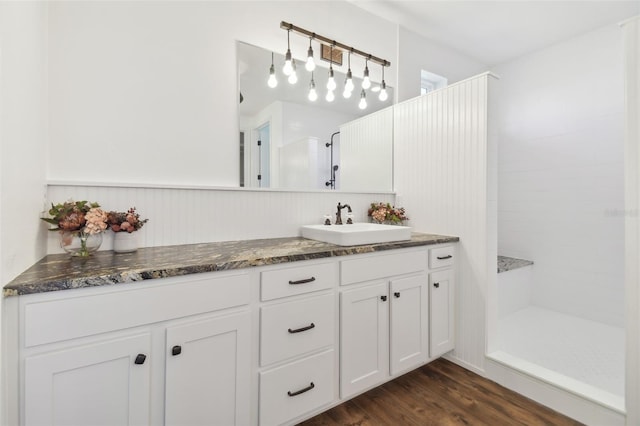 bathroom with vanity, tiled shower, and wood-type flooring