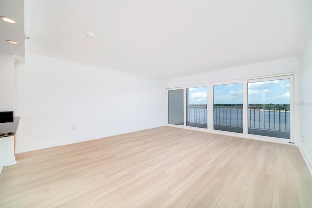 spare room featuring a water view and light wood-type flooring