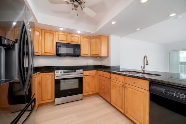 kitchen featuring sink, black appliances, light hardwood / wood-style flooring, and dark stone counters