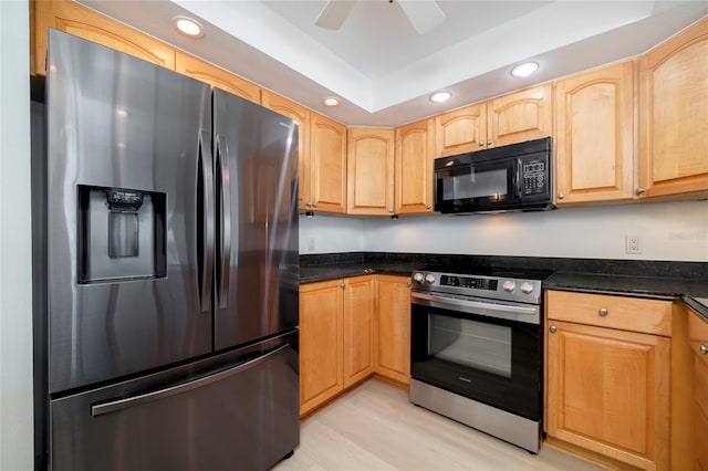 kitchen with light brown cabinets, ceiling fan, appliances with stainless steel finishes, dark stone counters, and light hardwood / wood-style flooring