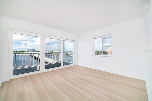 unfurnished room featuring a water view, light wood-type flooring, and crown molding