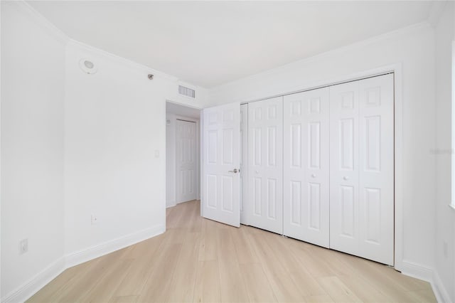 unfurnished bedroom with crown molding, light hardwood / wood-style flooring, and a closet