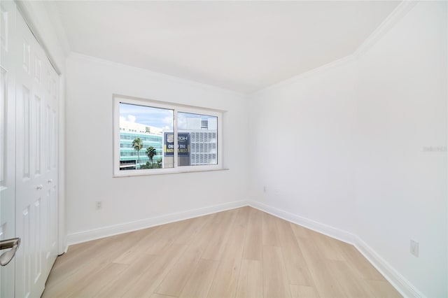 unfurnished room with ornamental molding and light wood-type flooring